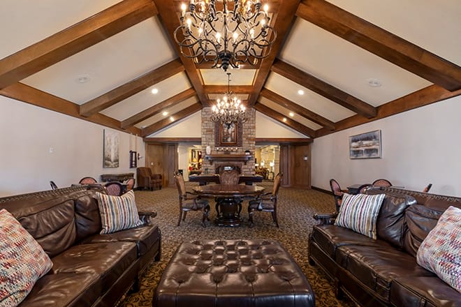 A luxurious living room with vaulted ceilings, wood beams, and elegant chandeliers.