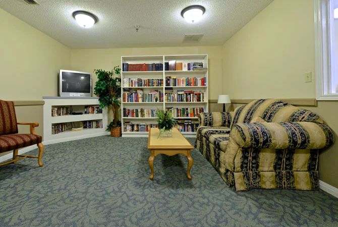 A cozy living room with a sofa, television, and bookshelves filled with books.