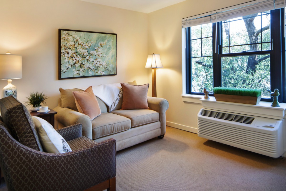A cozy living room with a sofa, armchair, and artwork on the wall.