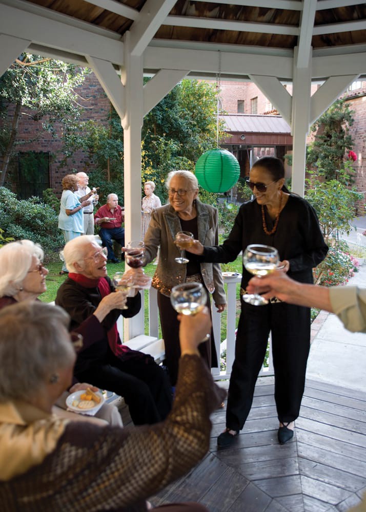 A group of people enjoying a celebration outdoors with glasses of wine.