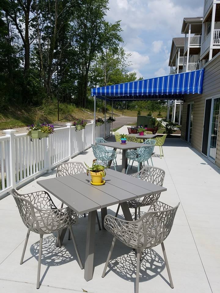 An outdoor patio with modern furniture and a blue-striped awning on a sunny day.