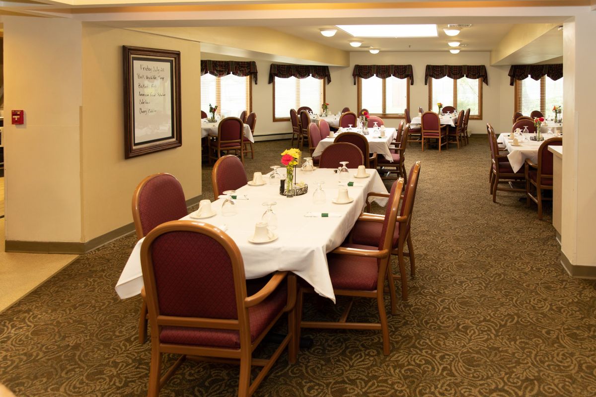 A formal dining room with neatly arranged tables and chairs, set for guests.