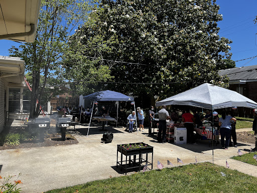 A vibrant outdoor gathering featuring tents and a barbecue setup under a clear blue sky.