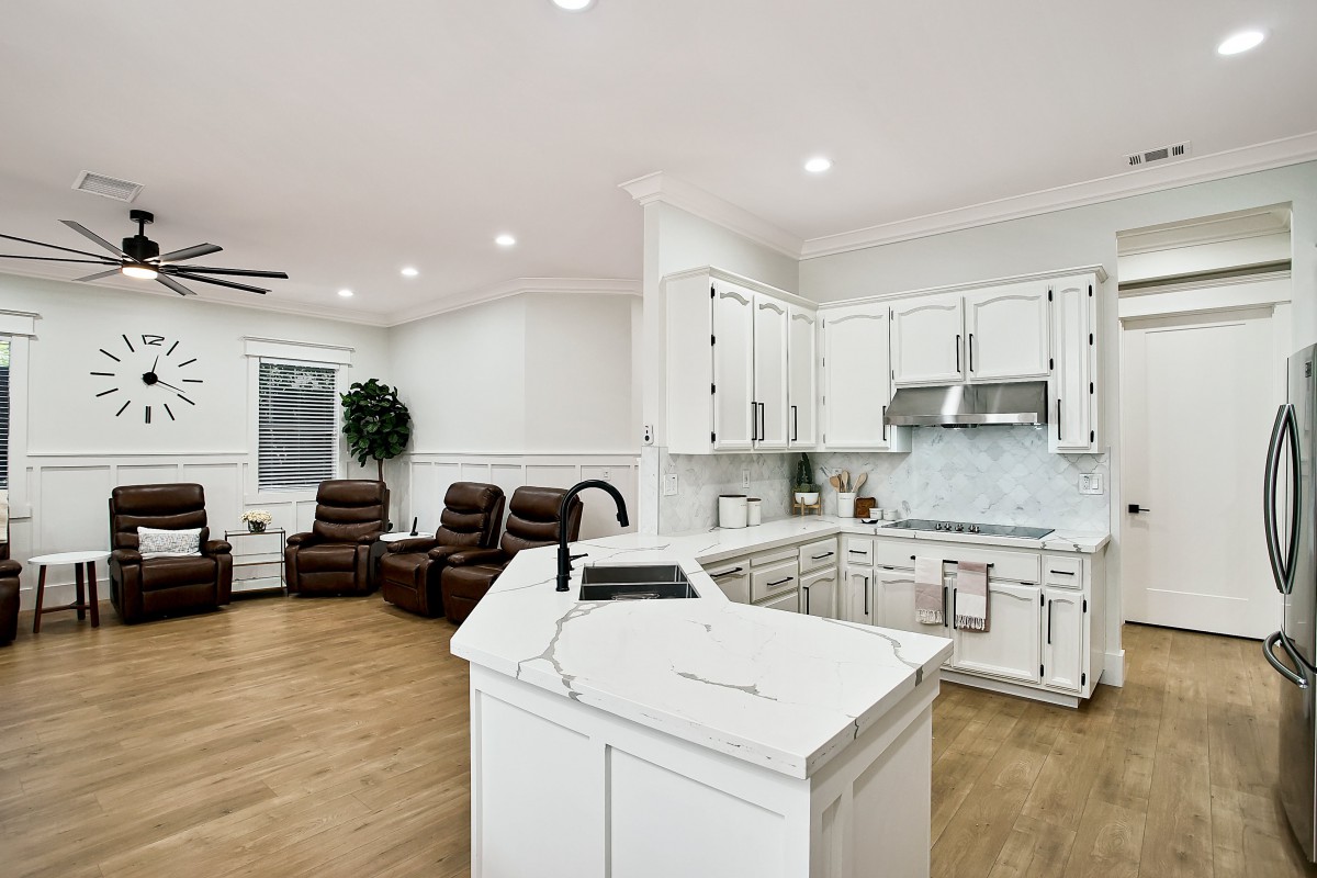 A modern open-concept kitchen and living room with white cabinetry and wood flooring.
