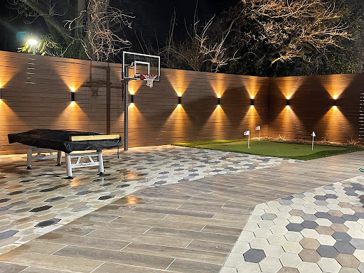 A beautifully lit outdoor space featuring a basketball hoop and elegant landscaping.