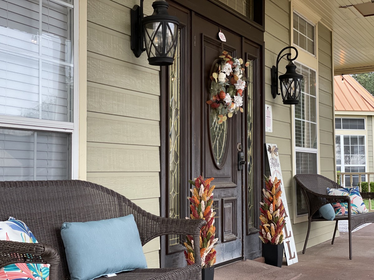 A cozy front porch with fall decorations and comfortable seating.