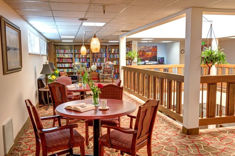 A cozy library space with tables, chairs, and bookshelves, offering a warm and inviting atmosphere.