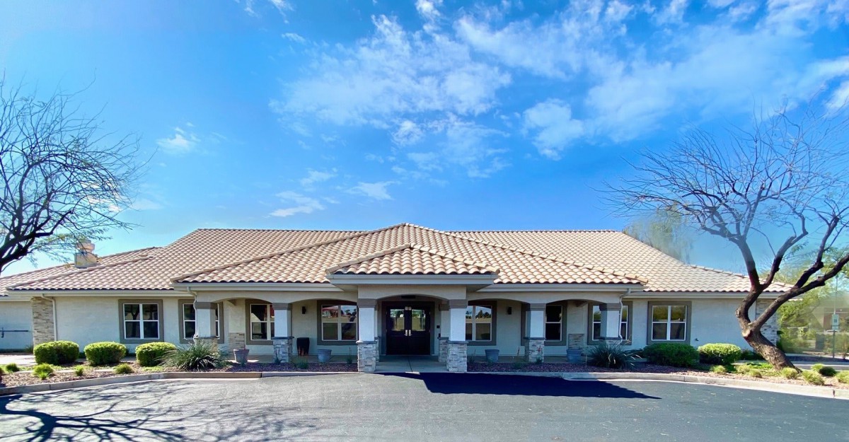 A single-story building with a tiled roof under a partly cloudy sky.
