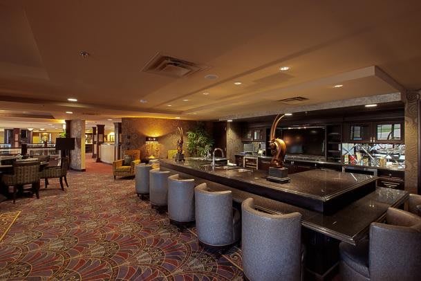 A cozy bar area with a long counter and plush seating, warmly lit and elegantly decorated.