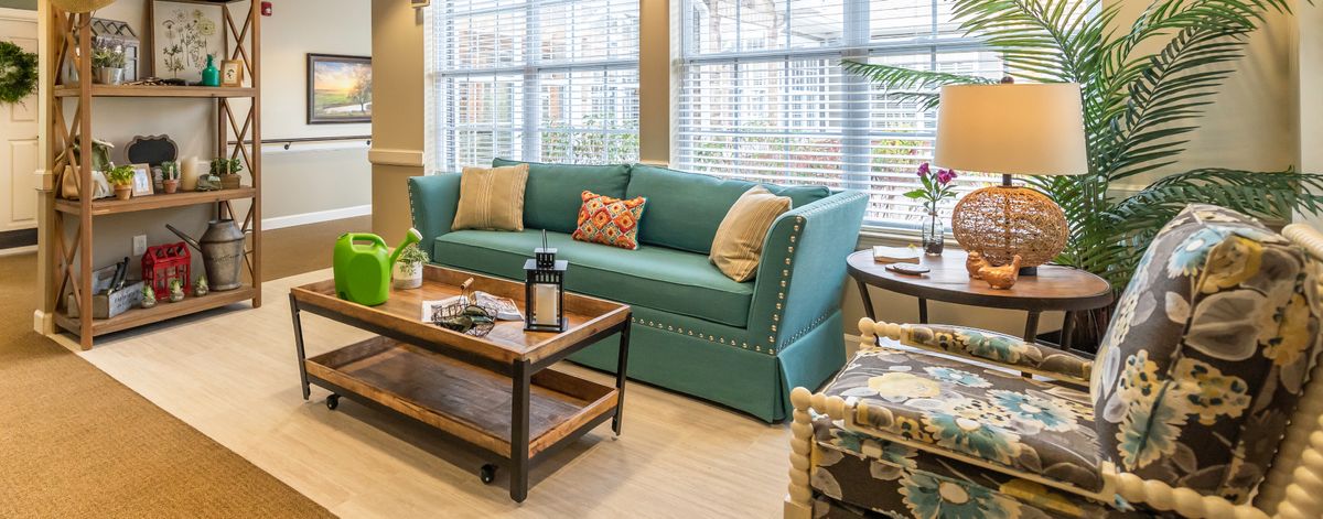 A cozy living room with a teal sofa and a wooden coffee table in front of large windows.