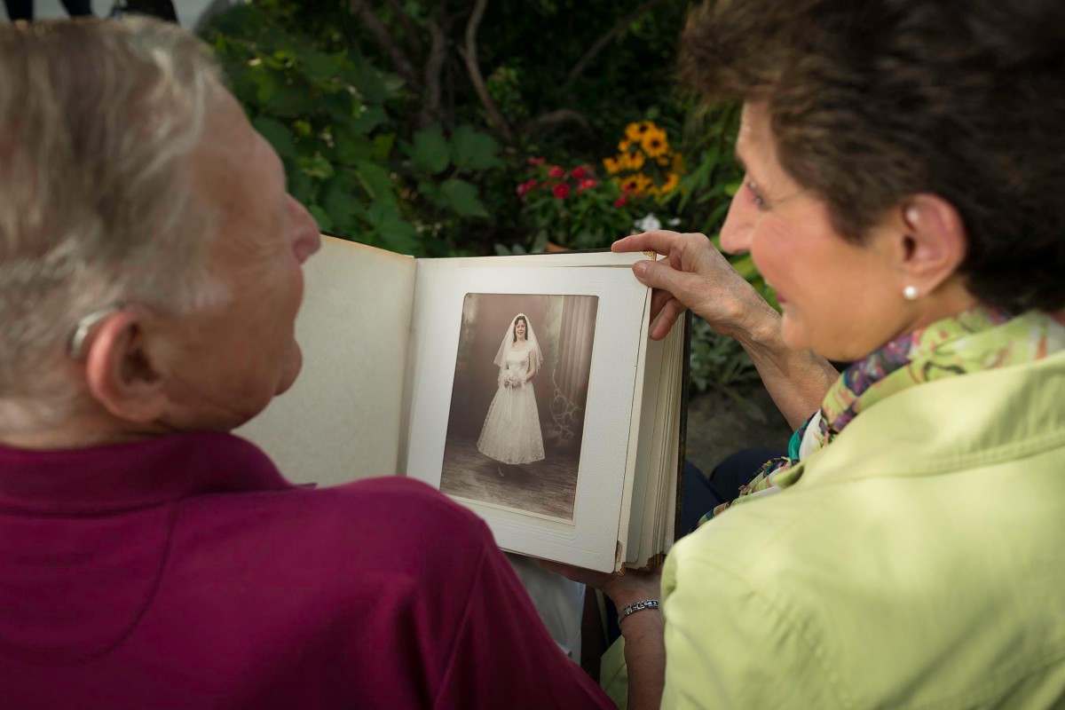 Two people looking at an old photograph in a photo album.