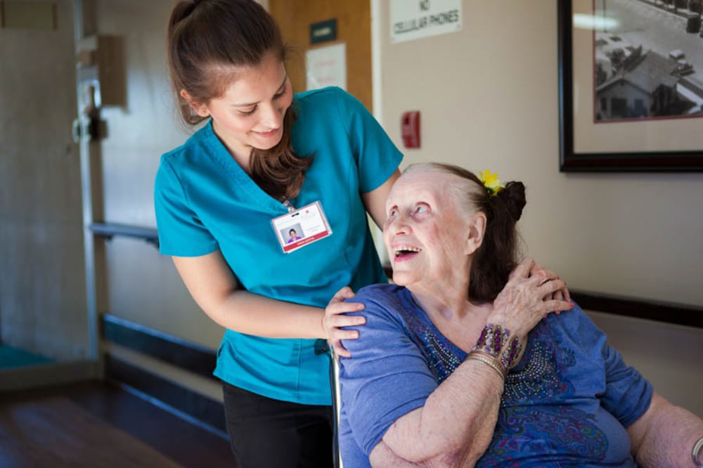 A caregiver provides support to a senior citizen in a healthcare setting.