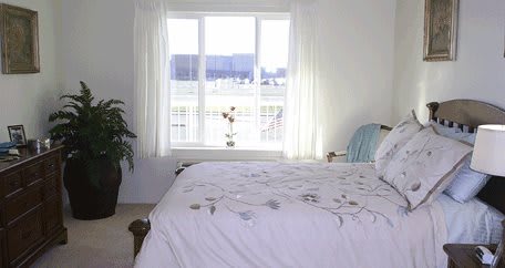 A bright bedroom with a large window allowing natural light to illuminate the room.