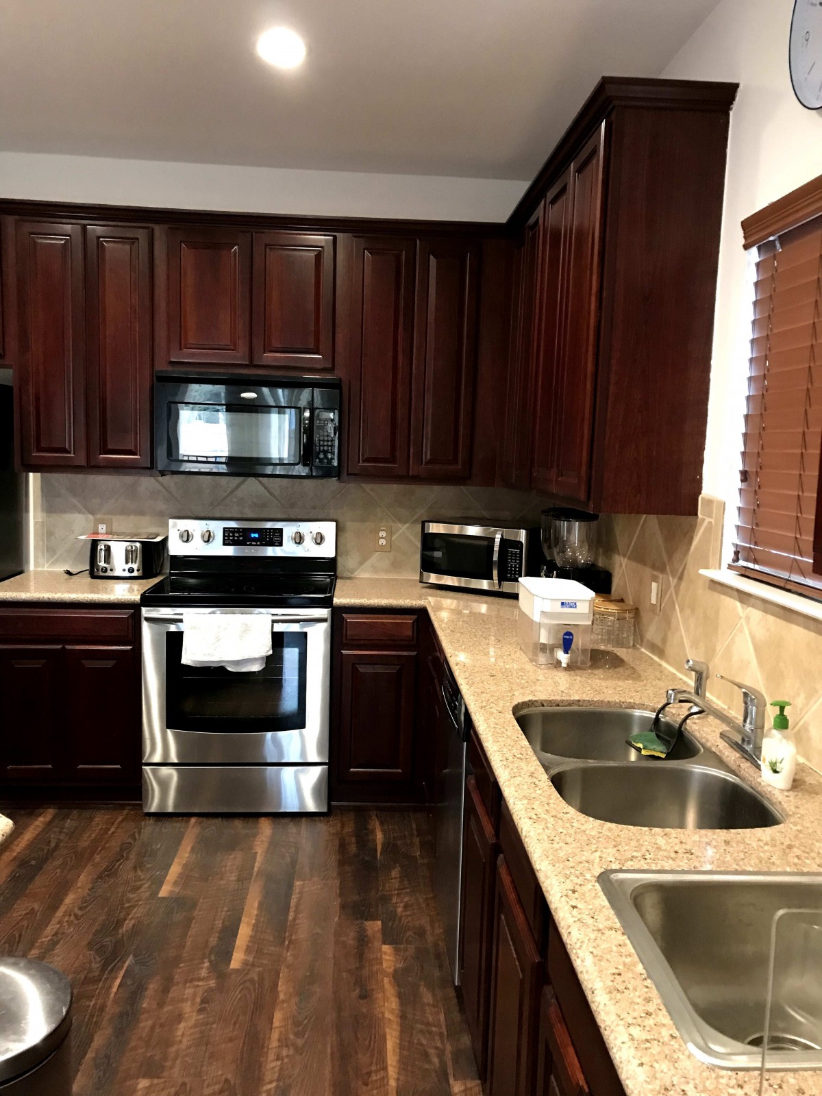 A modern kitchen with dark wood cabinets and stainless steel appliances.