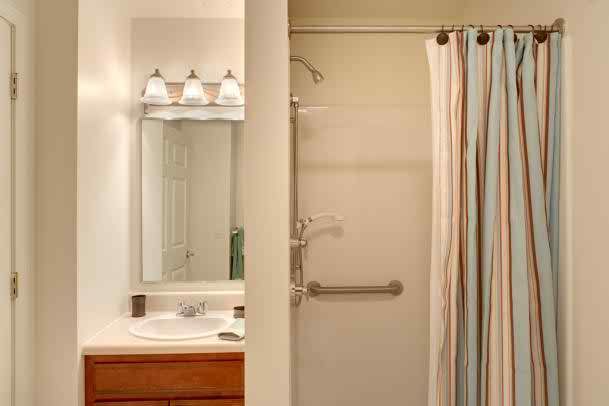 A bathroom featuring a sink with a mirror, a shower with a curtain, and overhead lighting.