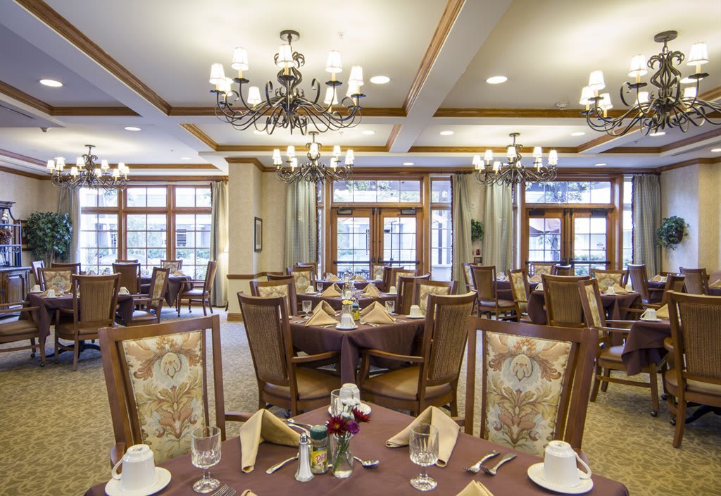 An elegant dining room with neatly arranged tables and chandeliers.