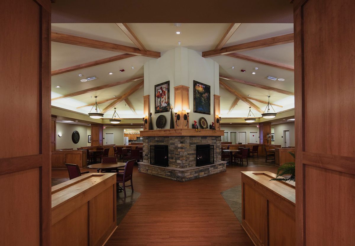 A cozy restaurant interior featuring wooden furniture and a central fireplace.
