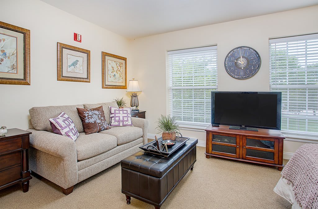 A cozy living room with a beige sofa, a television, and decorative artwork on the walls.
