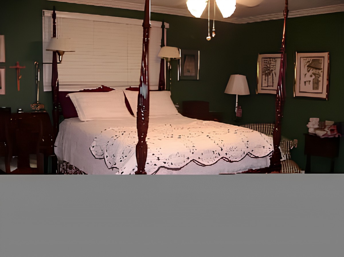 A cozy bedroom featuring a four-poster bed with decorative bedding, surrounded by lamps and artwork.