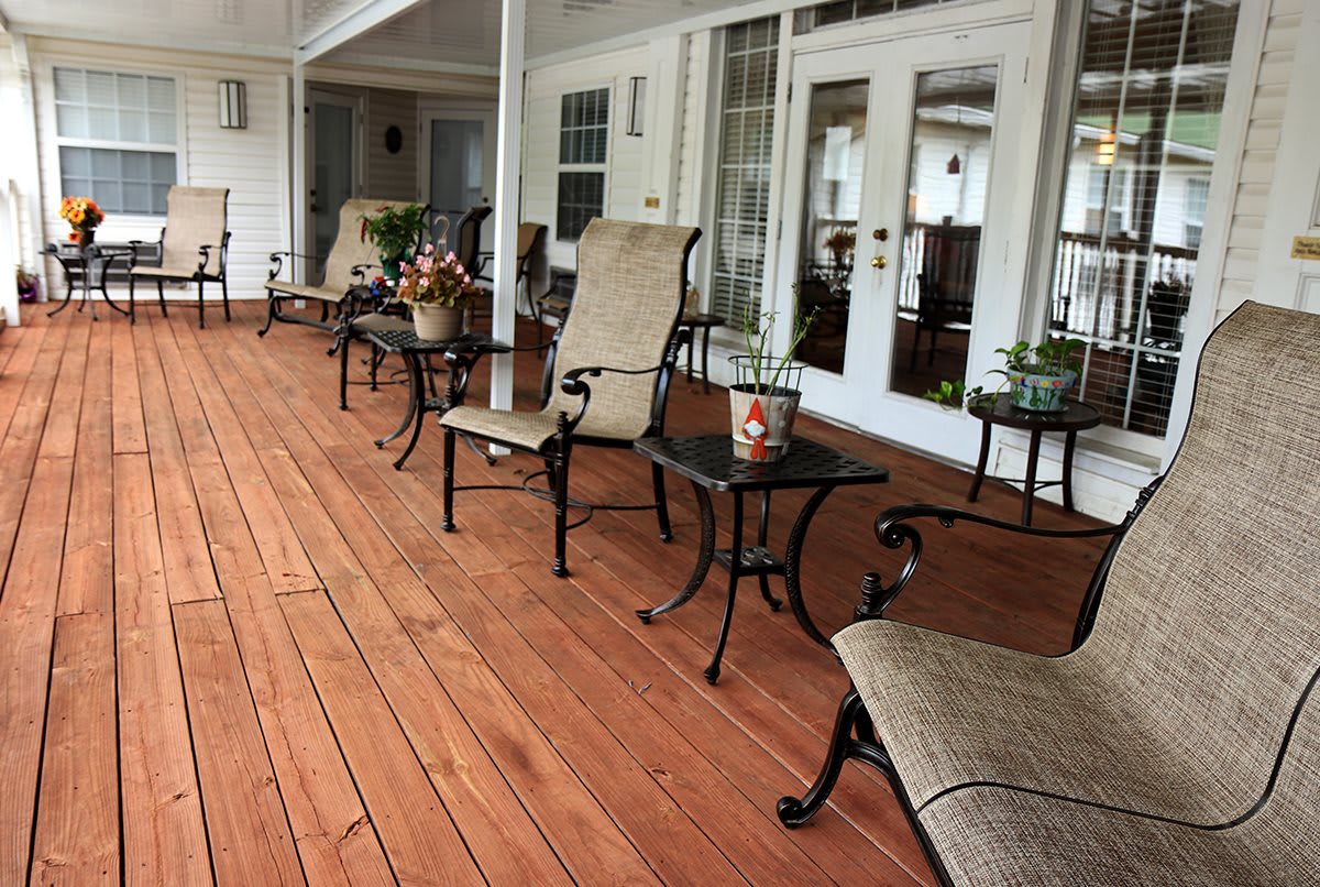A cozy porch with comfortable seating and plants on a wooden deck.