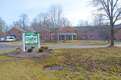 A view of a residential building with a welcoming sign in front, surrounded by trees.