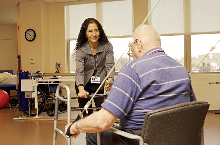 A physical therapist assists an elderly man during a rehabilitation session.