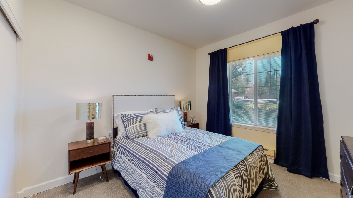 A cozy bedroom with a neatly made bed and large window.
