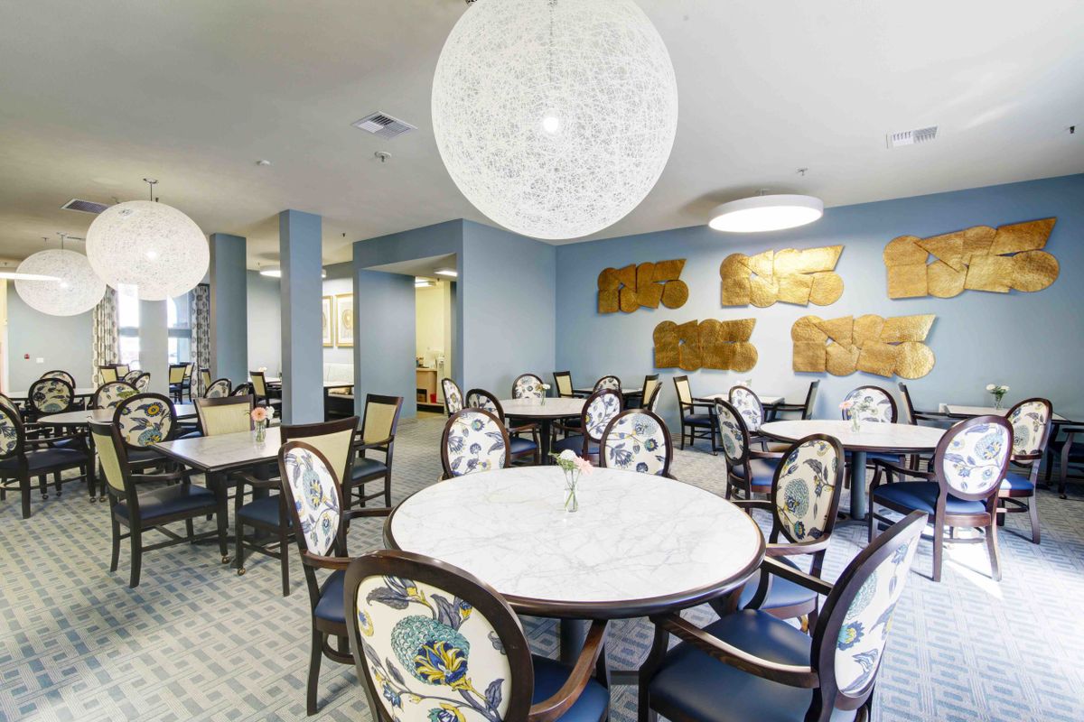A modern dining room with round tables, elegant chairs, and stylish lighting fixtures.