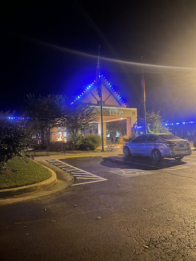 A well-lit building at night adorned with blue lights, surrounded by a parking lot.