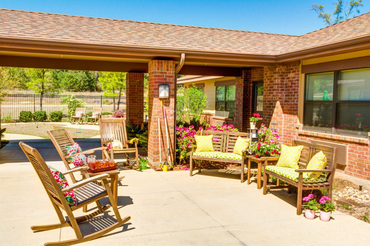 A cozy outdoor patio with rocking chairs and plants on a sunny day.