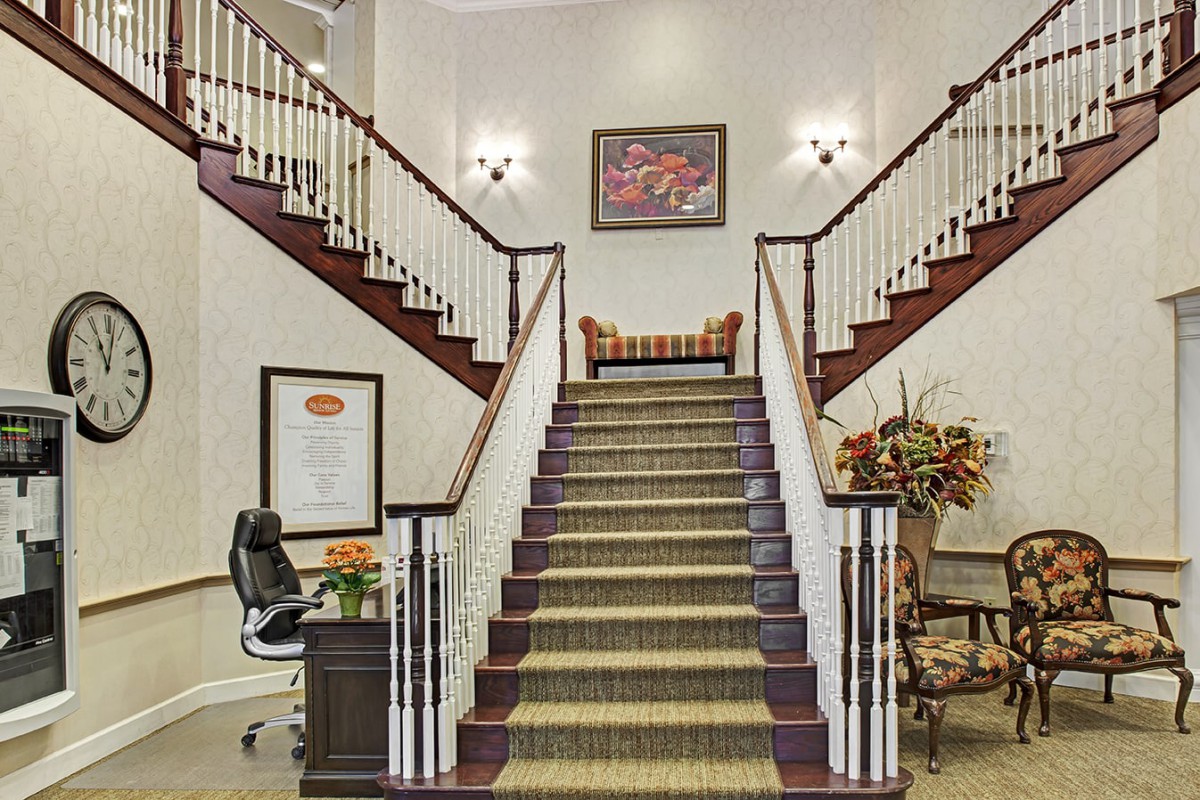 A well-lit lobby featuring a grand staircase with elegant decor.