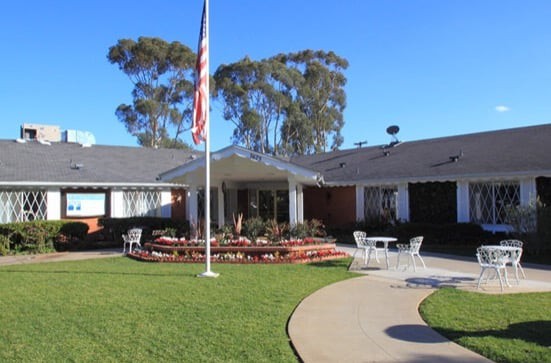 A well-maintained building surrounded by a garden with an American flag in front.