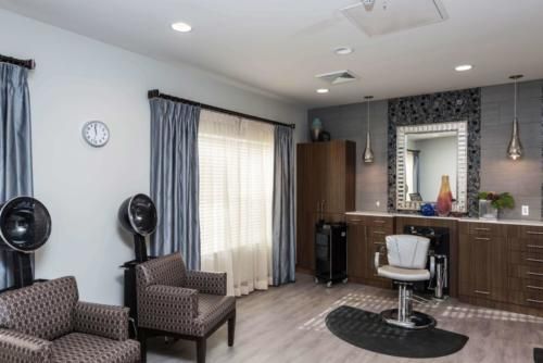 A modern salon interior featuring a hairdressing chair, large mirror, and comfortable seating.