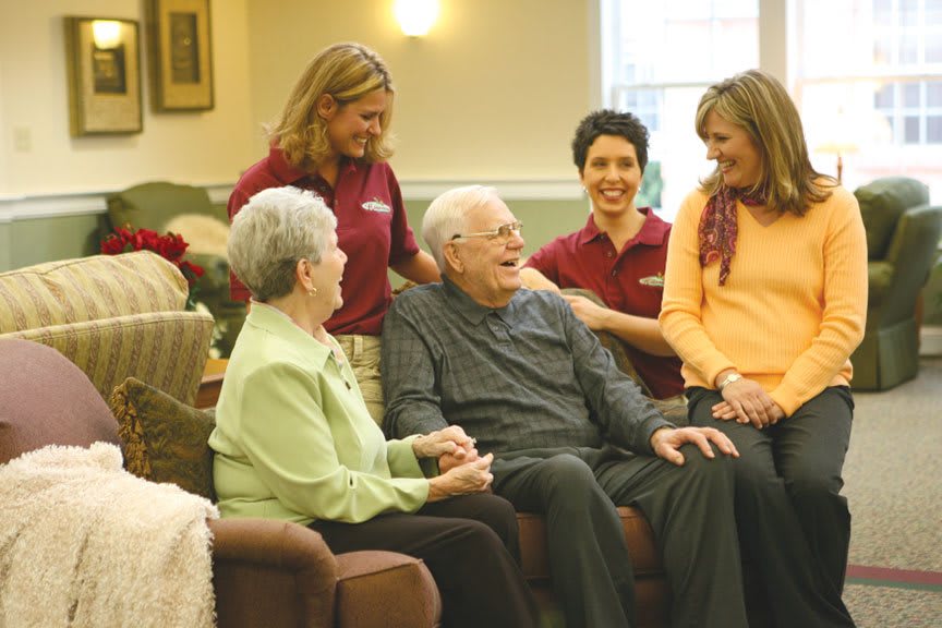Healthcare workers interacting with seniors in an assisted living facility.