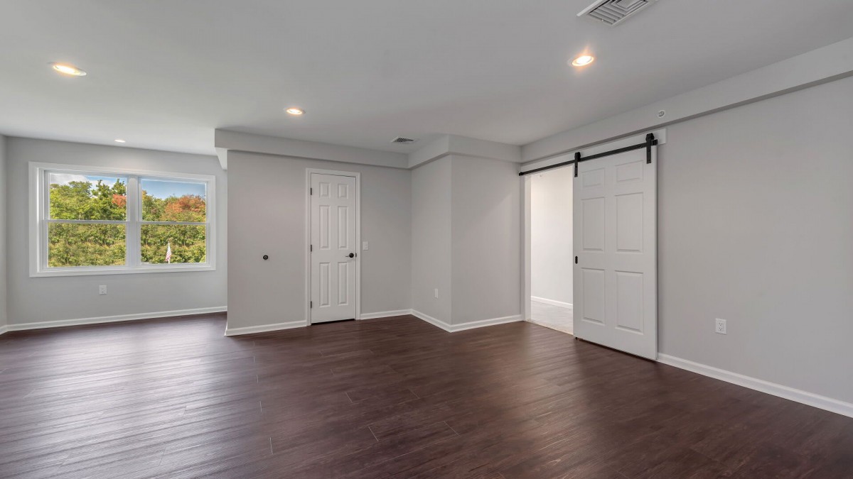 A modern, empty room with wood flooring and recessed lighting.