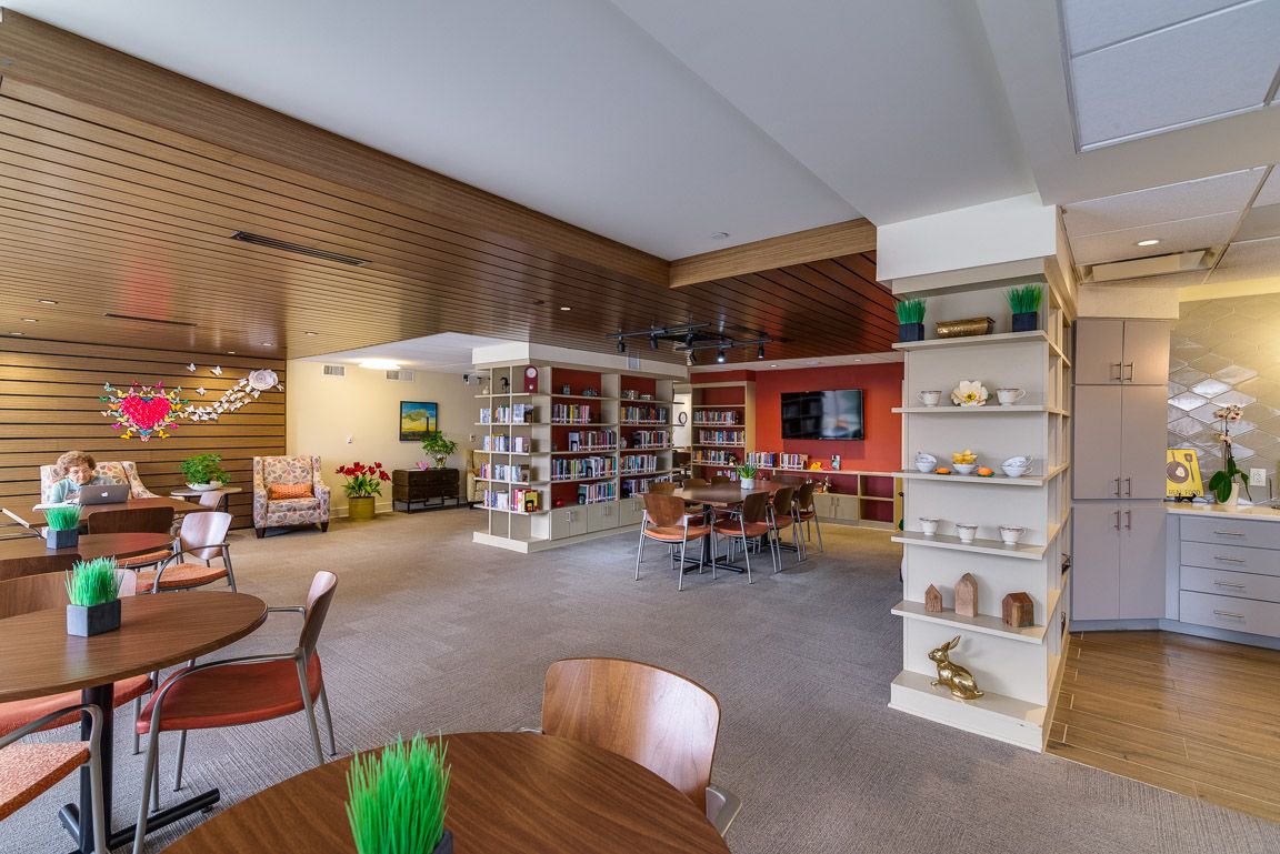 A cozy library interior featuring bookshelves, tables, and chairs for reading.