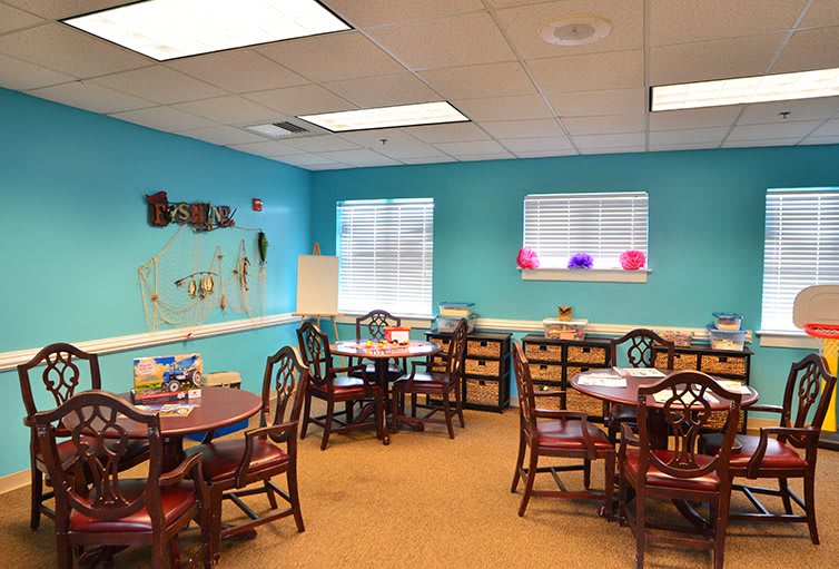 A colorful classroom with tables and chairs arranged for children's activities.