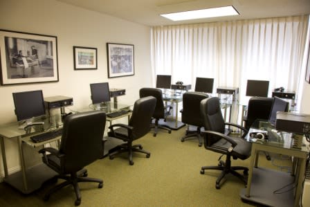 An empty office conference room with chairs and desks equipped with computers.