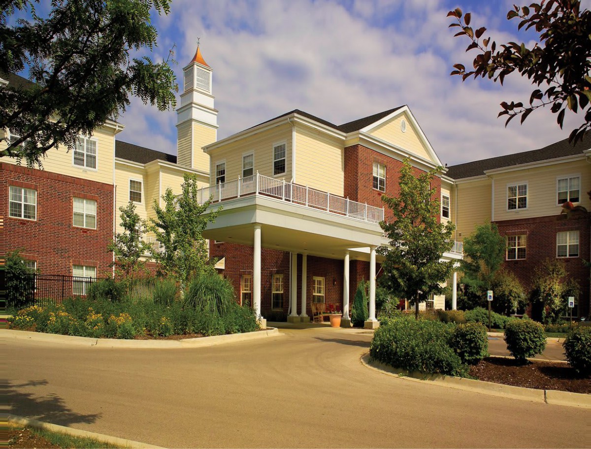 A modern residential building with landscaped gardens under a clear sky.
