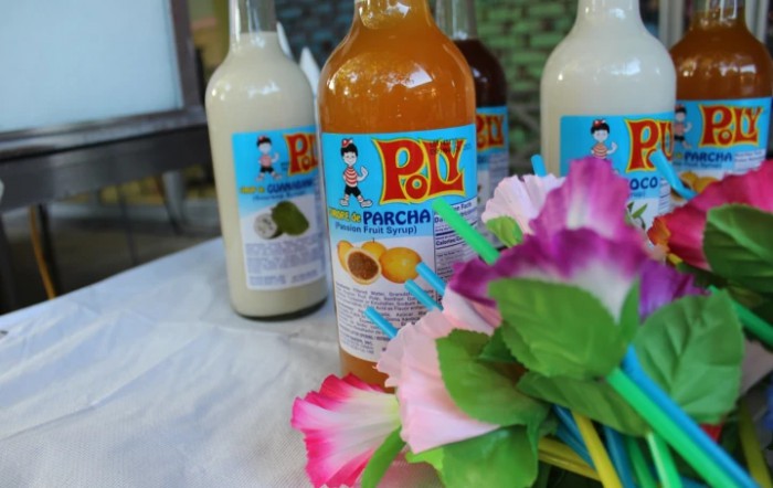 Bottles of Poy beverages featuring a passion fruit (marcha) flavor, displayed with colorful flowers.