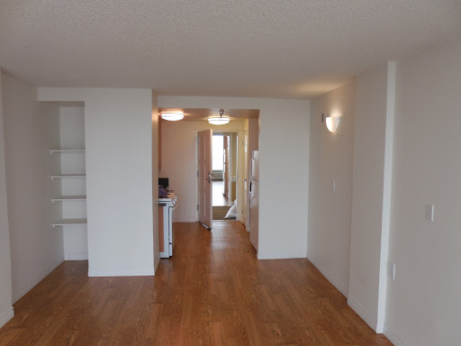 A spacious and modern apartment interior featuring wooden flooring and bright lighting.