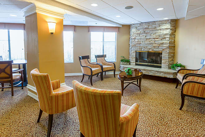 A modern living room with striped chairs and a stone fireplace.