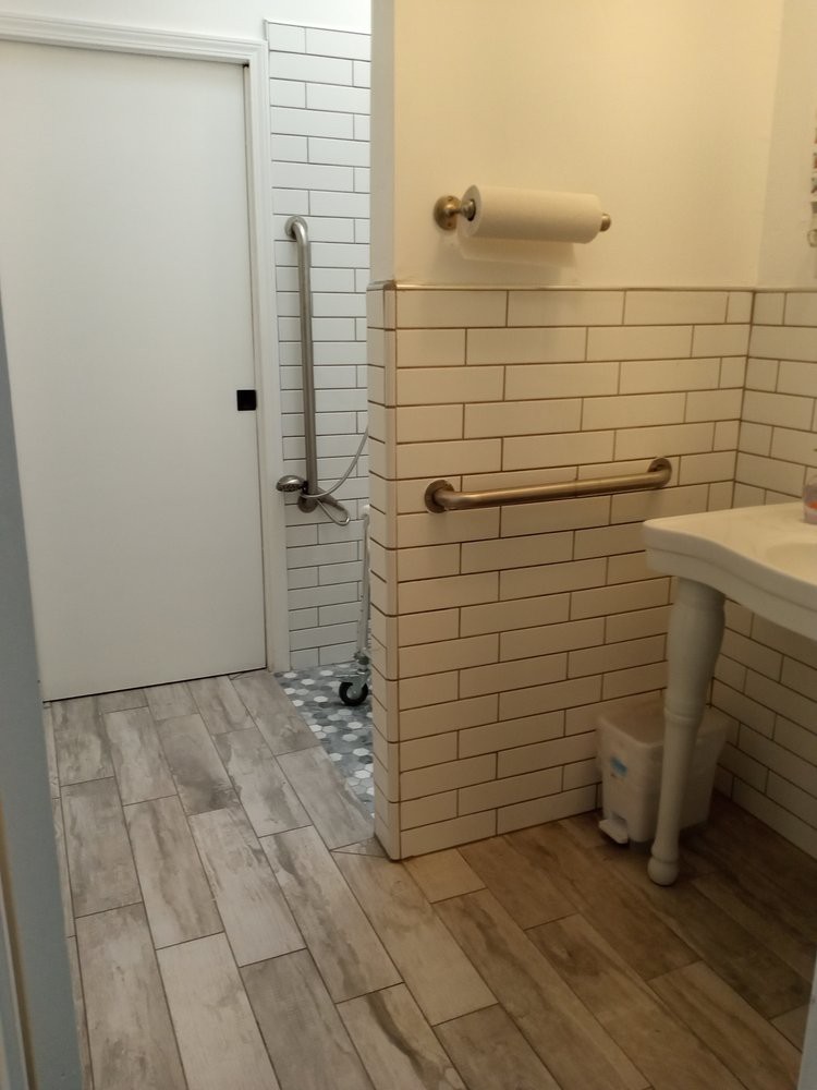 A modern bathroom with tiled walls, a sink, and wooden flooring.