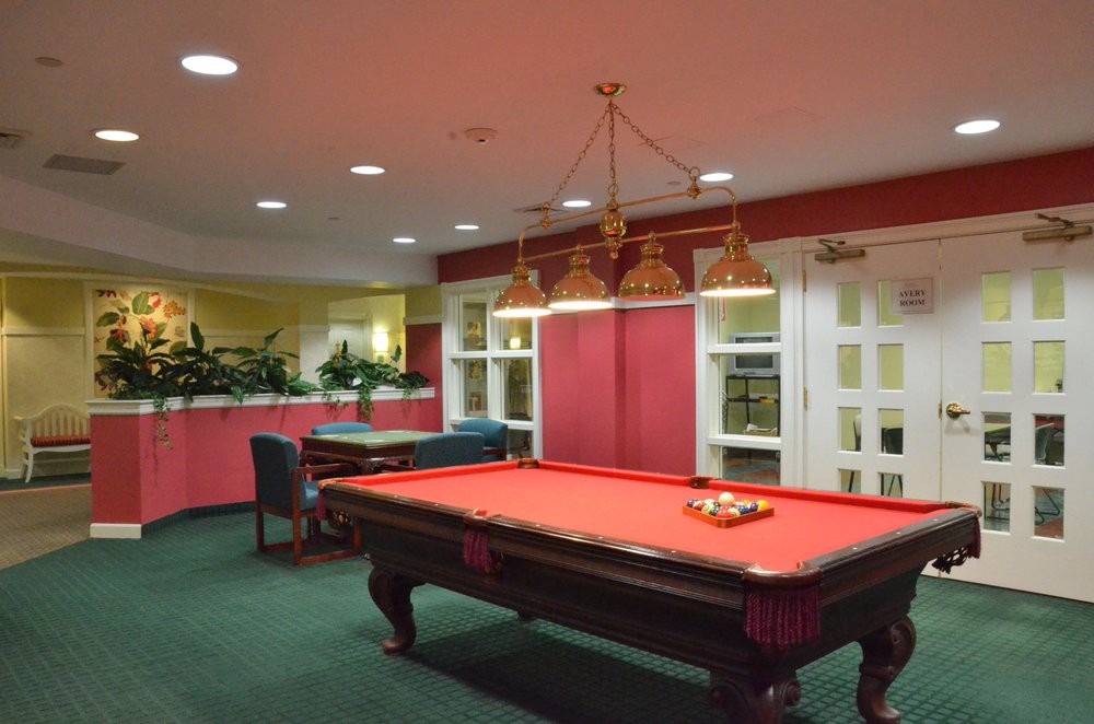 A stylish billiard room featuring a red pool table under a classic hanging light fixture.