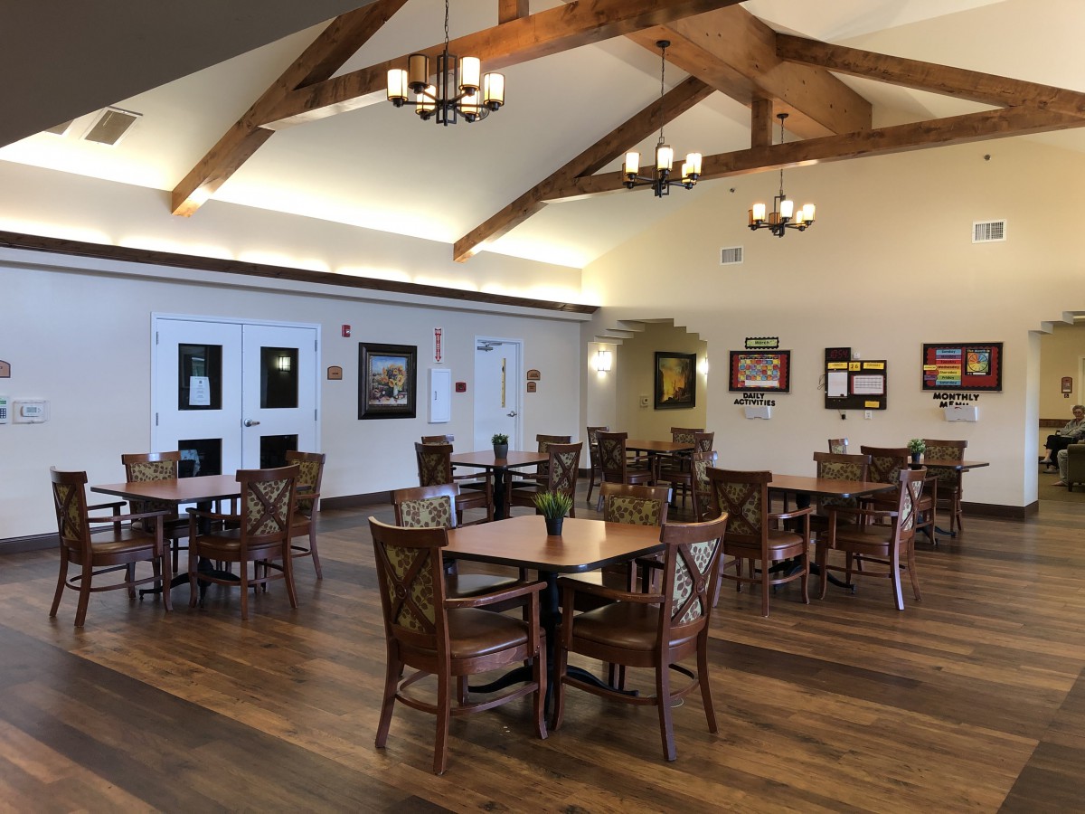 A spacious dining area with wooden tables, chairs, and decorative chandeliers.