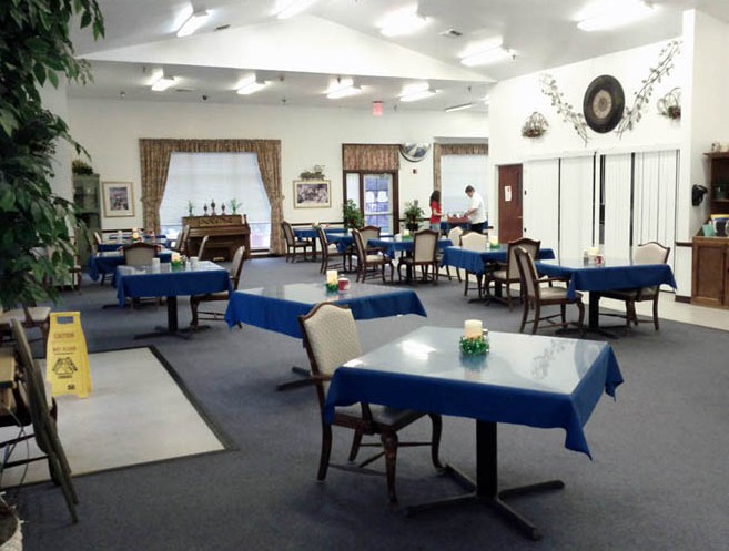 An empty dining room with tables covered in blue tablecloths.