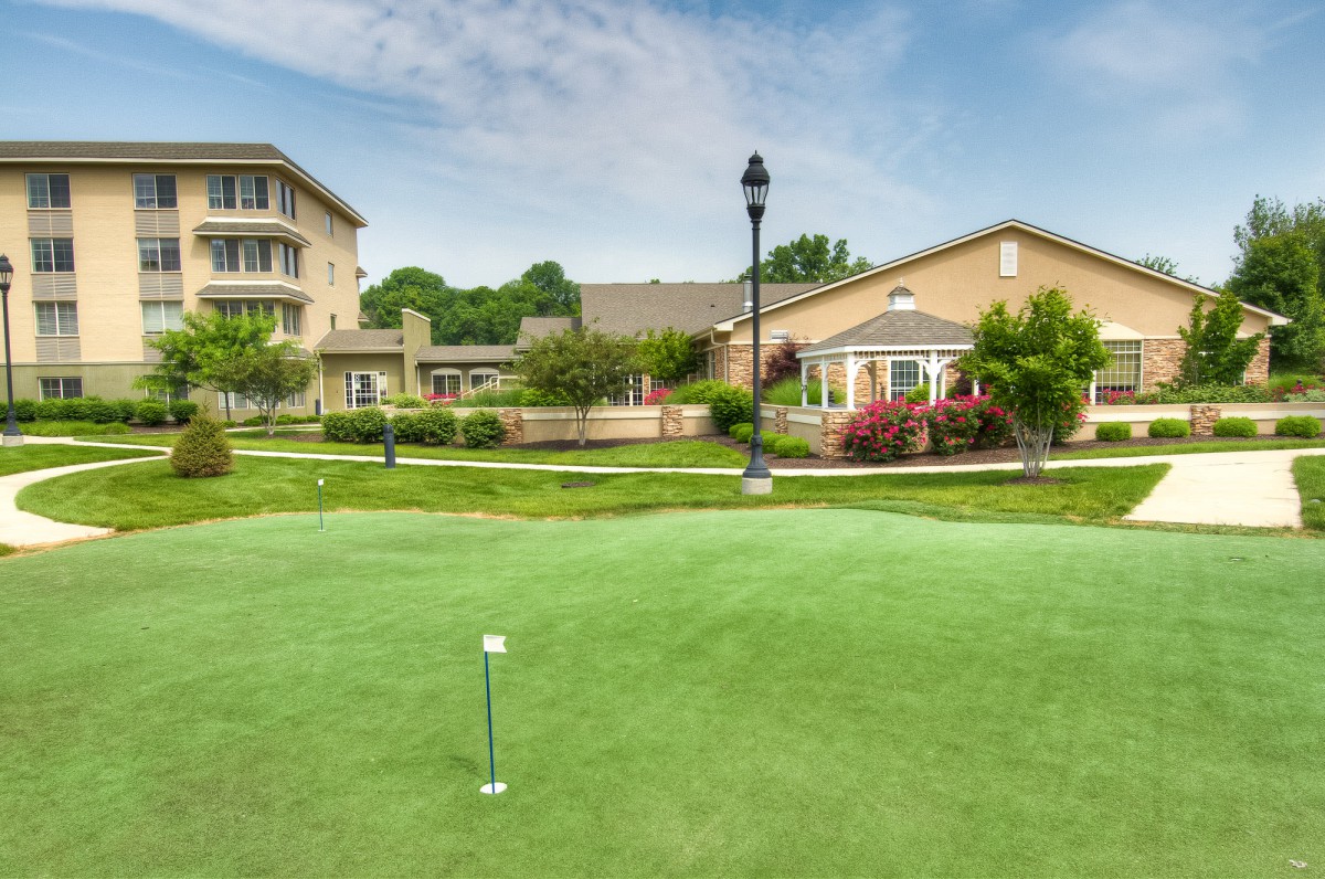 A scenic view of a putting green surrounded by buildings and lush greenery.