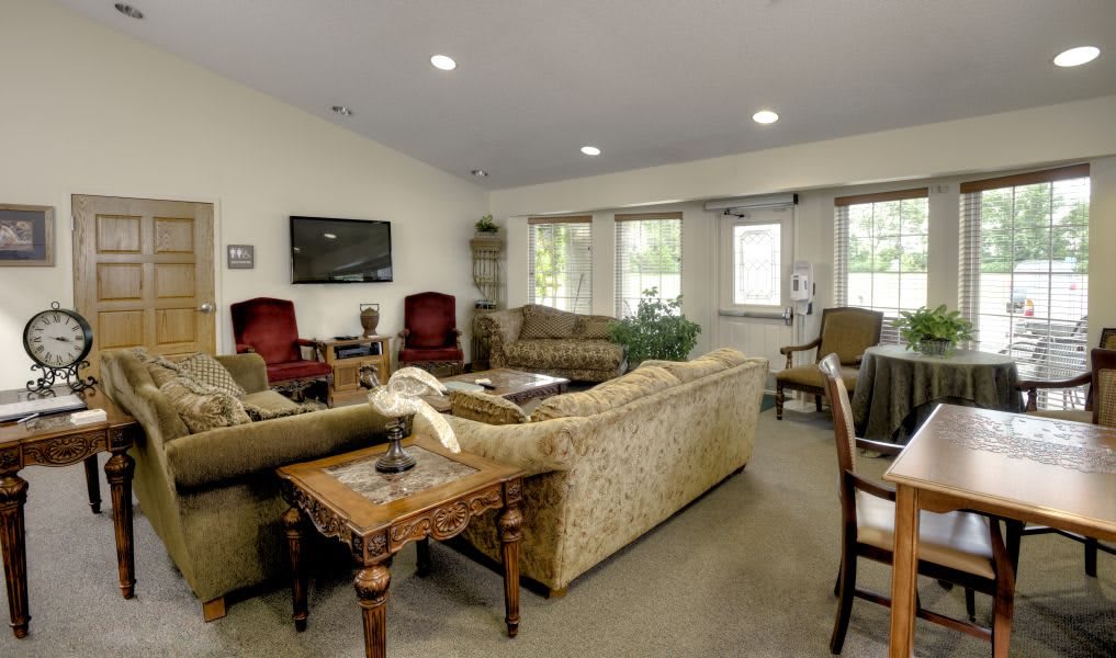 A cozy living room with multiple seating options, a television, and large windows.