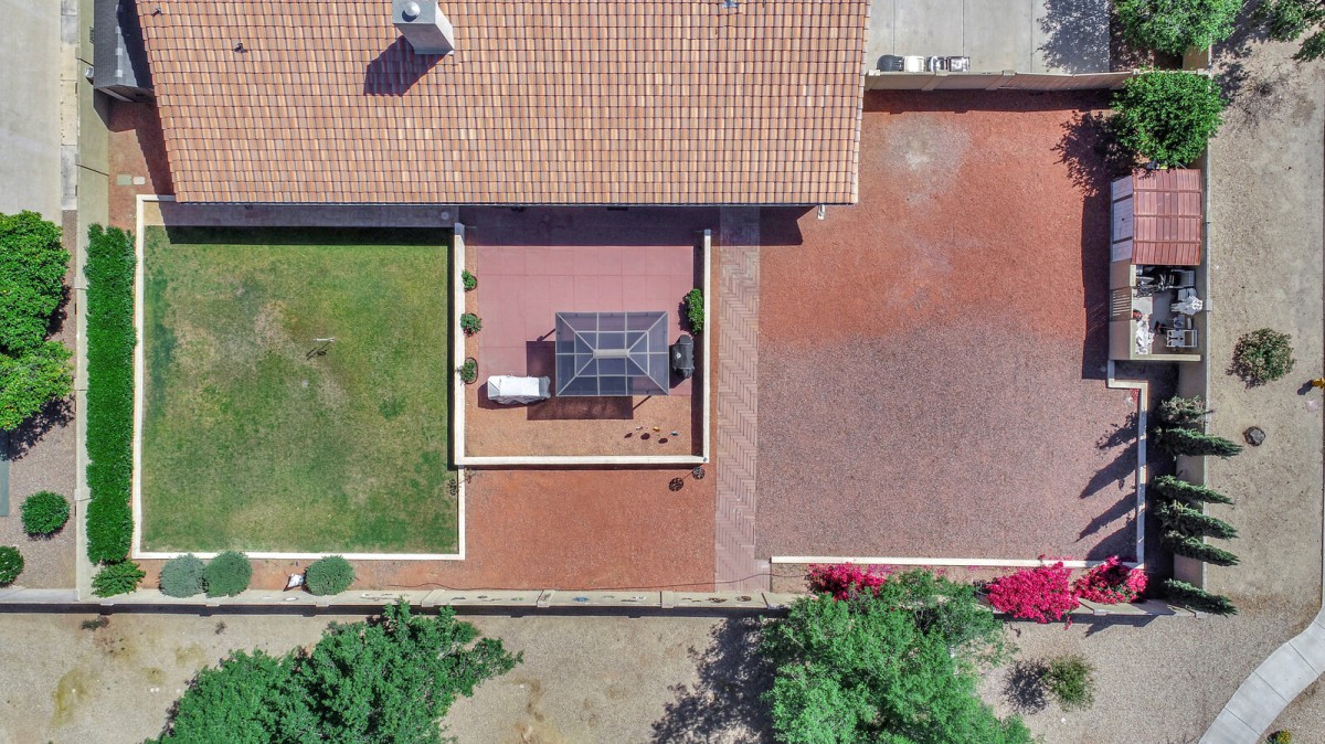 Aerial view of a house with a tiled roof, featuring a backyard patio, solar panels, and a green lawn.
