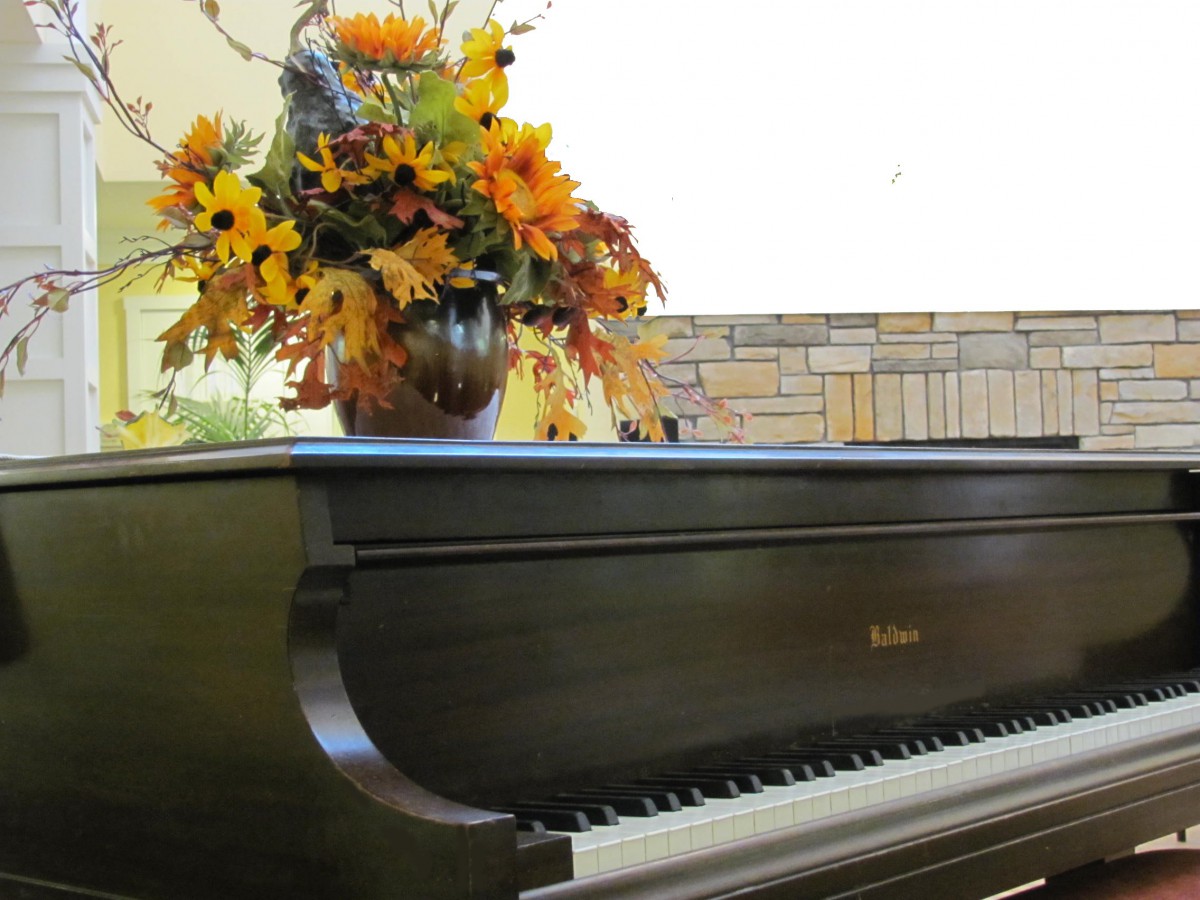 A grand piano adorned with a vibrant autumn floral arrangement.